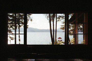 view of lake and mountains and dock sunny through the silhouette of a window