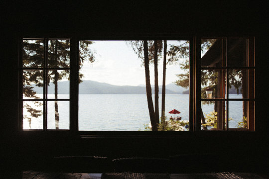 Fototapeta view of lake and mountains and dock sunny through the silhouette of a window