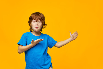 An indignant red-haired boy shows with his hand to the side 