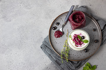 Jar of delicious homemade black currant curd, custard or jam with natural yogurt and fresh berries...