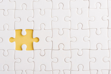 Top view flat lay of paper plain white jigsaw puzzle game texture incomplete or missing piece, studio shot on a yellow background, quiz calculation concept