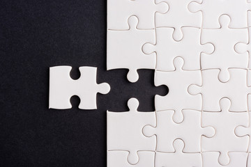 Top view flat lay of paper plain white jigsaw puzzle game texture last pieces for solve and place, studio shot on a black background, quiz calculation concept