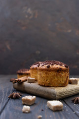 Tasty spicy muffins with chocolate streusel and cinnamon and anise star on wooden board, rustic background.