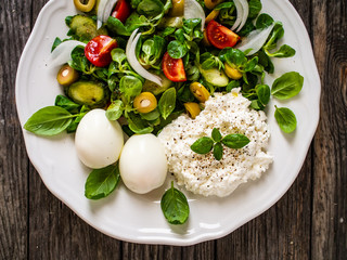 Delicious breakfast - boiled eggs with cottage cheese and vegetables served on wooden table
