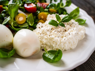 Delicious breakfast - boiled eggs with cottage cheese and vegetables served on wooden table
