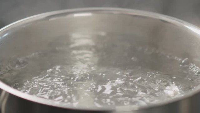 Slow motion boiling water in a pot closeup turn off heat