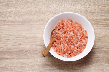 Himalayan pink salt in ceramic cup on wooden table