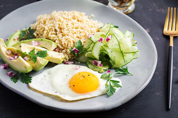 Diet menu. Healthy lifestyle. Bulgur porridge, fried egg and fresh vegetables -  cucumber and avocado on plate.