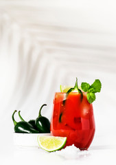 Spicy alcoholic cocktail with vodka, tomato juice, jalapeno pepper, lime and salt, white background, hard light, copy space