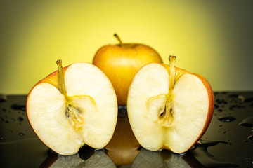 two halves of an apple with a splash and splashing of water on a yellow background