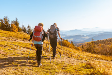 Two elderly people with large backpacks to hike through the autumn mountains,  concept of active...