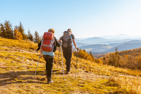 Two elderly people with large backpacks to hike through the autumn mountains,  concept of active recreation in old age