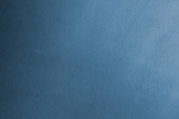 Blue paper texture background with some small white spots and dirt. Gradient light. Top view with copy space for input the text.