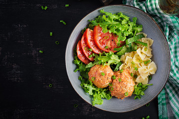 Italian pasta. Farfalle with meatballs and salad on dark background. Dinner. Top view, overhead. Slow food concept