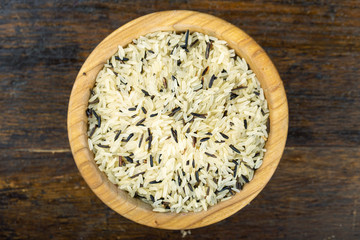 Wild rice in a wooden bowl on a wooden table.