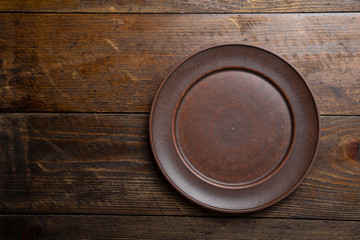 Clay plate on wood background, top view.