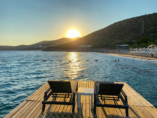 Obraz premium empty beach and sunbeds in the evening, lounge chair standing on the pier