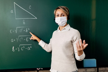 School teacher wearing face mask while teaching mathematic in the classroom.