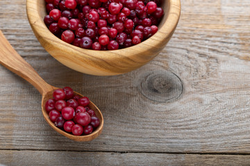 Fresh cranberries in a bowl on a wooden table.