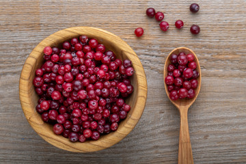 Fresh cranberries in a bowl on a wooden table.
