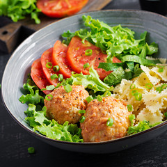 Italian pasta. Farfalle with meatballs and salad on dark background. Dinner. Slow food concept