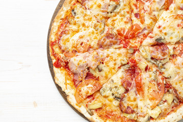 Delicious pizza served on wooden plate on wood background. Top view.