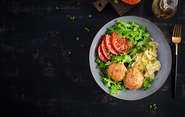 Italian pasta. Farfalle with meatballs and salad on dark background. Dinner. Top view, overhead. Slow food concept