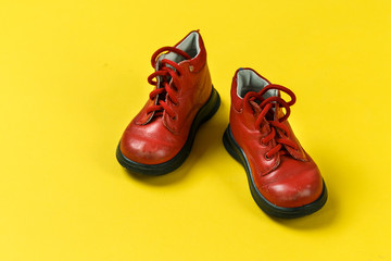 Children's shoes in red on a yellow background.