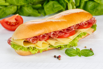 Sub sandwich baguette with salami ham and cheese on wooden board