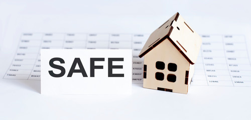 Closeup of house wooden model with blank for text SAFE on the chart background.