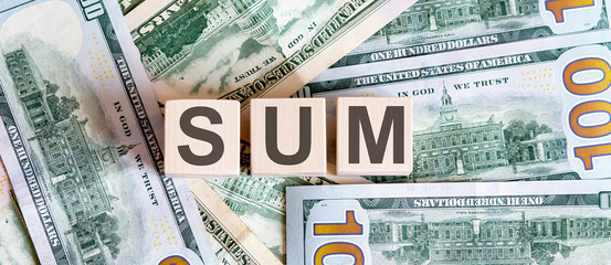 Concept words SUM on wooden blocks on a beautiful background from dollar bills.