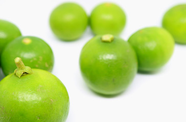 Closeup a vibrant green lime with another scattered on white background