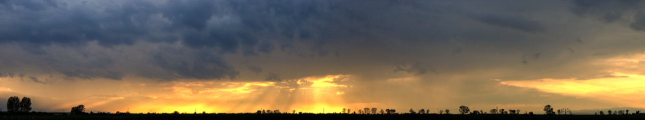 Obraz na płótnie Canvas cloudy sunset over field landscape panorama