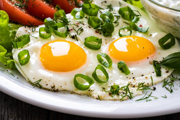 The best summer dinner - sunny side up eggs, boiled potatoes, cucumbers in yogurt  and fresh vegetables served on wooden table
