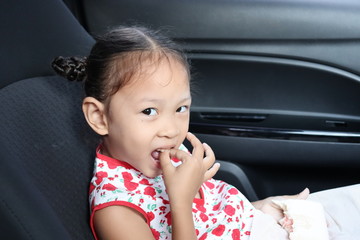Asian girl eating bread for breakfast in the car. On the way to school