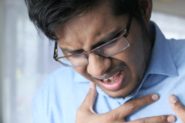 young man suffering heart and holding his chest.