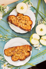 Baked sandwiches with apples and white flowers on blue table