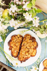 Two sandwiches with apples and white flowers on blue table