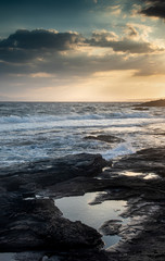 Naklejka na ściany i meble Rocky seashore with windy waves at sunset. Xilofagou Larnaca Cyprus