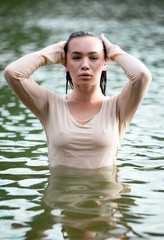 Young European woman with dark hair in wet closes posing in water 