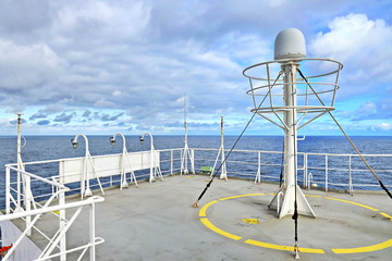 Ship structures, masts, antennas, funnel, ship wheelhouse against the blue sky and clouds. Vessel traveling at ocean. © masterskuz55