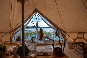 Girl sitting near the tent in nature