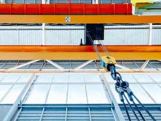 Overhead crane and machine inside factory building, industrial background.