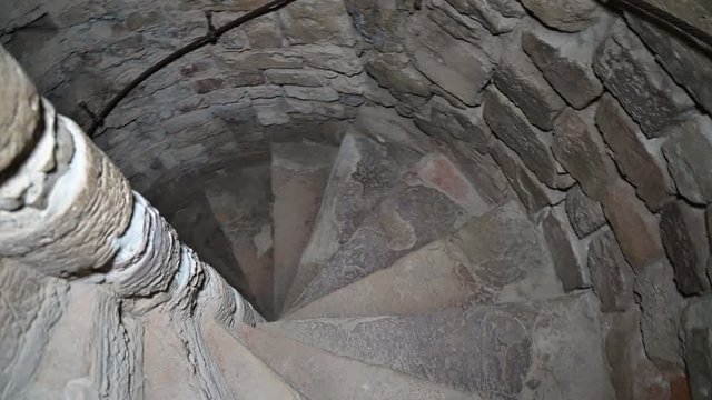 Descending the spiral staircase to the dungeon. Ancient stone staircase in the tower.