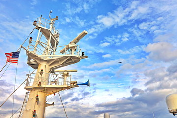 Ship structures, masts, antennas, funnel, ship wheelhouse against the blue sky and clouds. Vessel traveling at ocean. © masterskuz55