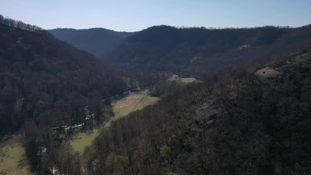 Flight above spring valley with curved tall river stream in the middle