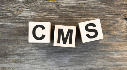 Acronym CMS - content management system. Wooden small cubes with letters isolated on white background with copy space available. Business Concept image.