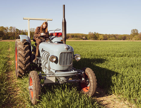 Landwirtschaft - Spass an alter Landtechnik, junge Frau auf einem Oldtimer-Traktor.