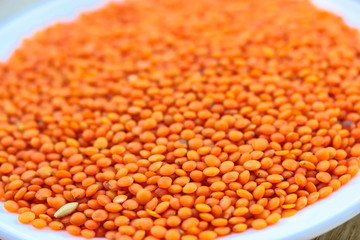 Red lentils in a round white plate: ingredients for a healthy diet natural meal