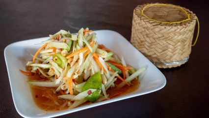 Spicy papaya salad and sticky rice on a table.